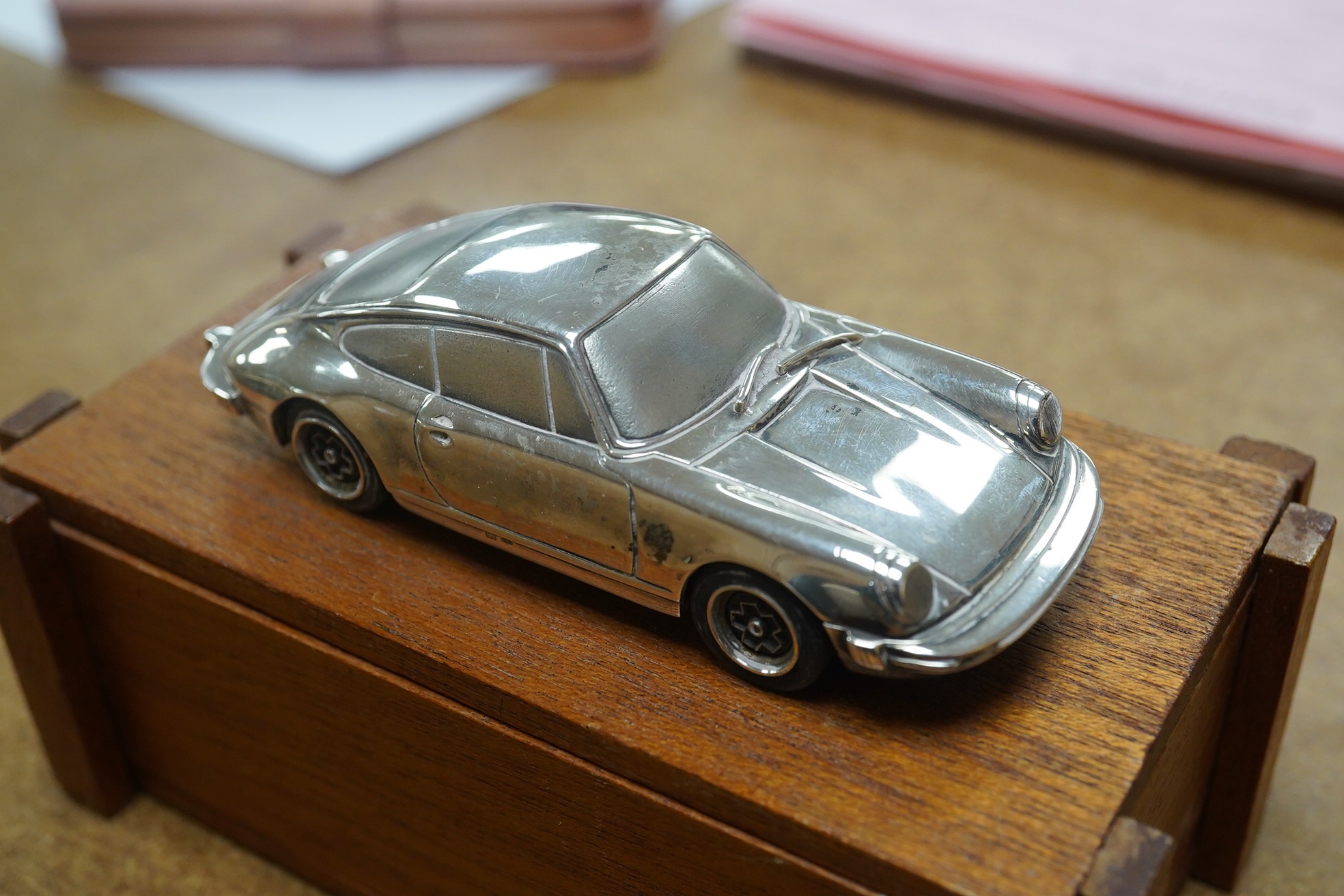 A 1:43 scale silver model of a Porsche 911, produced as a promotional model with details stamped to the base plate including; ‘Baujahr 1977, Porsche Design Produket, Sterling Silver 925’. Condition - fair to good, some m